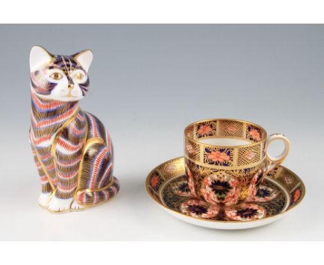 A Royal Crown Derby Imari seated car figure, with gold button, together with a Royal Crown Derby Imari coffee cup and saucer.