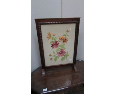 An oak framed embroidered fire screen