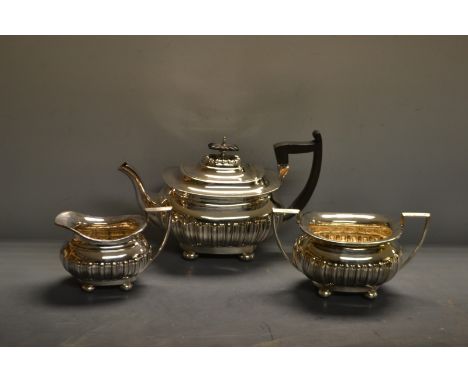 A Walker and Hall three piece EPNS boat shaped tea service, stop fluted, angular handles, bun feet
