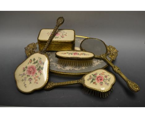 A gilt brass petit-point dressing table set, comprising oval tray, hand mirror, brushes, trinket box and cover (6)