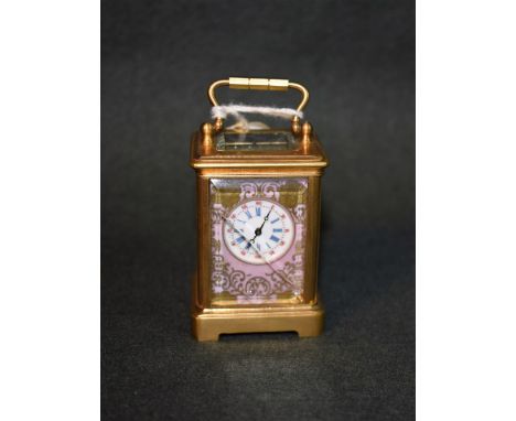 A miniature gilt brass French style carriage clock, the porcelain panels painted with flowers, swing handle, with key, 7cm hi