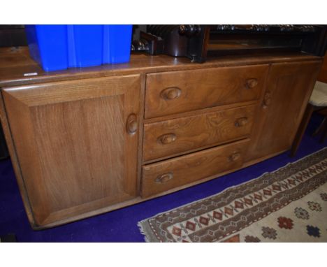 A mid stain Ercol sideboard having three central drawers , flanked by cupboard, on shepherds castors, width approx 155cm