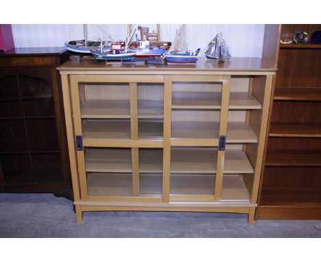 A light oak display cabinet enclosed by glazed sliding doors  