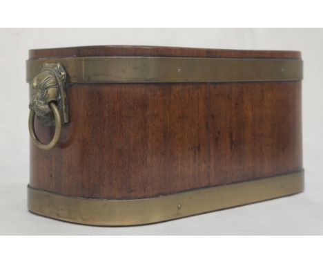 A Regency Brass-Bound Wine Cooler:
an oval square form mahogany cooler with two riveted brass bands.   Lion mask ring handles