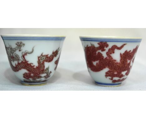 A Pair of  Chinese Iron Red Dragon Cups:
the sides decorated with dragons amongst clouds chasing pearls, the base bearing Che
