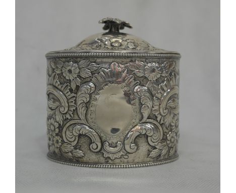 A Regency Silver Tea Caddy by W.B.:
an oval form tea caddy with embossed floral shell and scroll design, vacant cartouche to 