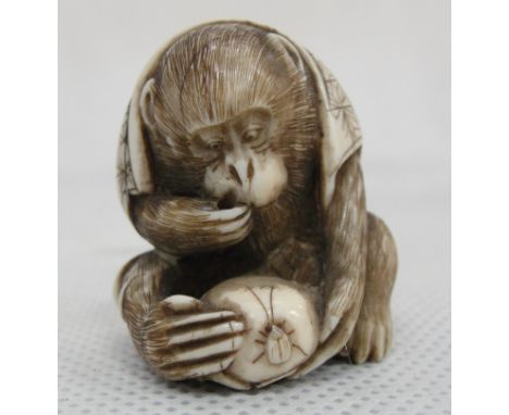 A Japanese Ivory Netsuke:
Meiji period
in the shape of a seated monkey wearing a robe and eating a gourd.  Artist's signature