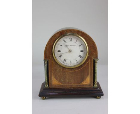 An Edwardian inlaid mahogany mantle clock, the circular dial marked Sir John Bennett Ltd, of domed form with brass pillar sup