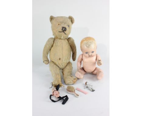 A straw stuffed teddy bear, 39cm, together with a composition baby doll with painted blue eyes, 28cm, a bisque doll's house d