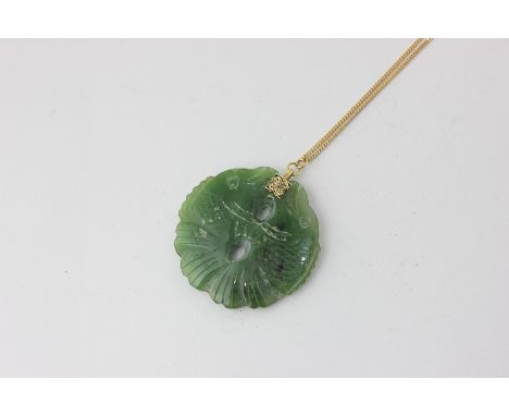 A pierced and carved jade pendant on a 9ct gold curb link neck chain