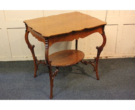 An oak occasional table, with shaped top and oval under shelf, on scroll carved slender cabriole legs, 75cm