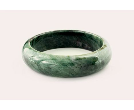 A contemporary jade bangle, of deep green and white marbled colouring and with a diameter of approximately 59mm.