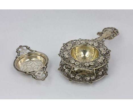 A German silver tea strainer and stand, early 20th century, of circular star shaped form, the handle fashioned as a Goddess p