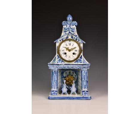 A 19th century Dutch Delft mantel clock, the top of architectural form with fleur-de-lys surmount, over a fireplace and mante