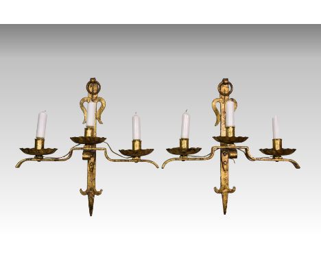 A pair of gilt metal Gothic style wall lights, probably early 20th century, the three scalloped sconces on a shaped twin bran