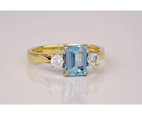 An 18ct yellow gold, aquamarine and diamond 3 stone ring, the step cut aquamarine weighing approximately 0.85ct and flanked b