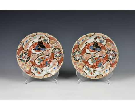 A pair of Chinese porcelain plates, 19th century, enamelled and painted with pairs of figures on verandas in iron red, black,