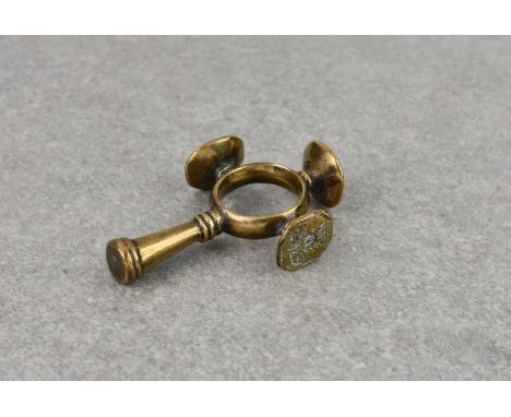 A polished bronze finger ring cruciform cigar tamper and seal combination, probably late 18th century, the intaglio seals dep