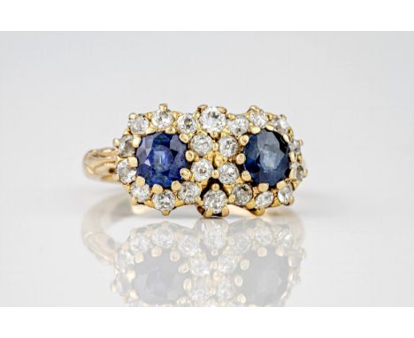 A yellow gold, sapphire and old cut diamond cluster ring, featuring two round cut sapphires surrounded by old cut diamonds. R