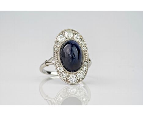 An antique diamond and sapphire plaque ring, featuring an inky blue cabochon sapphire to the centre, surrounded by an oval pl