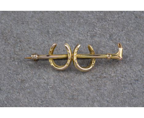 Horse riding interest - a vintage 9ct gold stick pin, in the form of a riding crop and two horseshoes, 1½in. (3.9cm.) long.