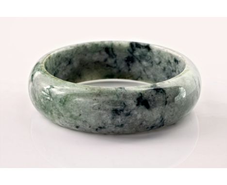 A contemporary jade bangle, of greyish green and white marbled colouring and with a diameter of approximately 57mm.