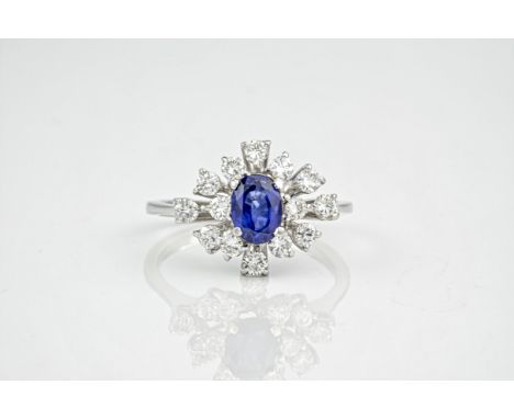 An 18ct white gold, sapphire and diamond dress ring., The oval cut sapphire weighing approximately 1.5ct and surrounded by 14