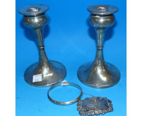 A pair of silver Art Deco candlesticks, weighted, Birmingham 1934 (a.f.); a silver sherry bottle label; a silver bangle