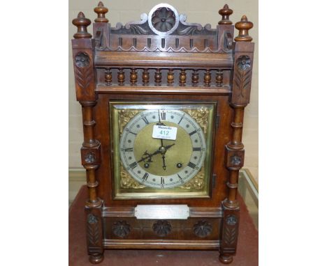 An Edwardian bracket clock in turned and carved oak case, with brass dial and chiming movement