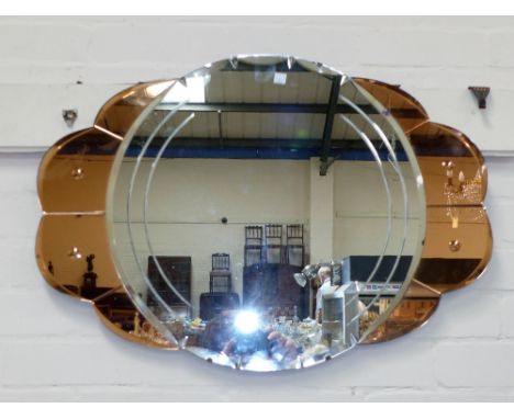 A 1930's peach glass circular wall mirror with convex central panel; a similar oval wall mirror