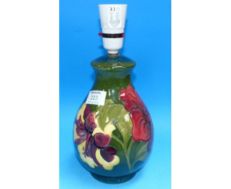 A Moorcroft baluster table lamp decorated with hibiscus against a green ground