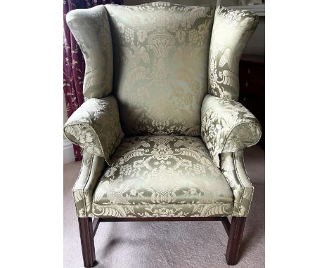 George III Chippendale style upholstered armchair, serpentine outsplayed wingback and arms on moulded square supports joined 