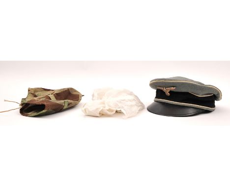 A German SS type visor cap, with reproduction SS eagle (no death’s head); a splinter camouflage helmet cover; and a snow camo