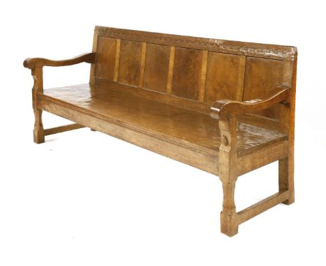 A Robert 'Mouseman' Thompson oak settle,the adzed frame with a penny moulded top over panels, a solid seat with scrolled arms