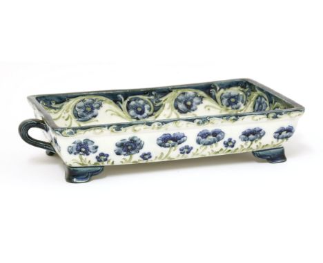 A Macintyre pottery 'Poppy' dish, designed by William Moorcroft, decorated in blue and green, with twin handles and raised on