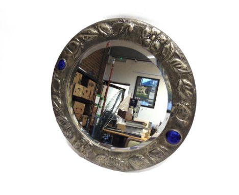 AN ARTS & CRAFTS STYLE CIRCULAR WALL MIRROR  the frame with floral decoration and inset with two enamel plaques