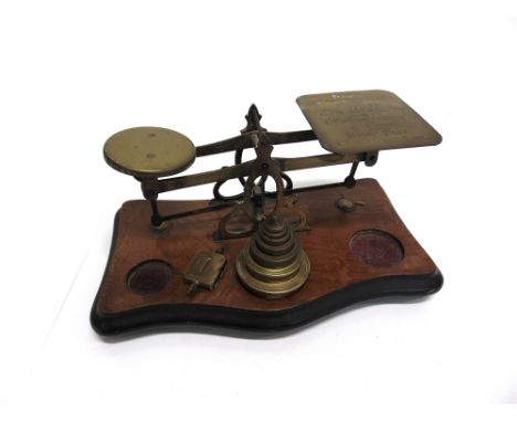 A SET OF BRASS POSTAGE SCALES  on shaped walnut base with graduated set of seven weights from 1/8 oz. to 8oz.; together with 