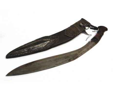 A NEPALESE KUKRI  the 42cm typically curved blade with a carved wood grip, in a leather scabbard with ornate silver coloured 