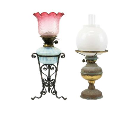 A wrought iron oil lamp. With opalescent glass reservoir and cranberry etched shade, height 53cm, together with another brass