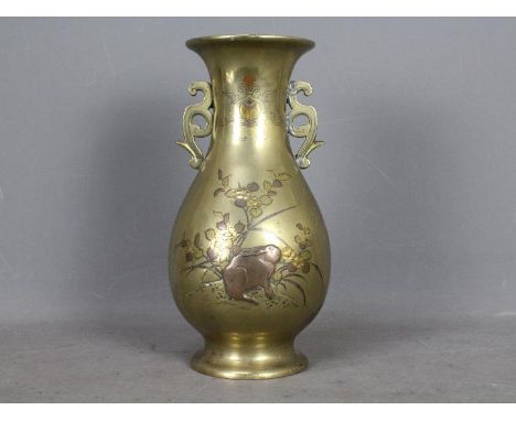 A large Oriental, twin handled brass baluster vase, decorated in relief with rabbit and floral motifs, approximately 30 cm (h