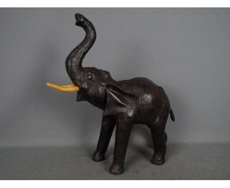 A vintage leather elephant with raised trunk, approximately 50 cm (h) to tip of trunk.Condition Report: One back leg is somew