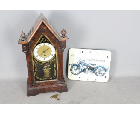 A steeple mantel clock with key and pendulum and a modern wall clock depicting a Harley - Davidson motorcycle.