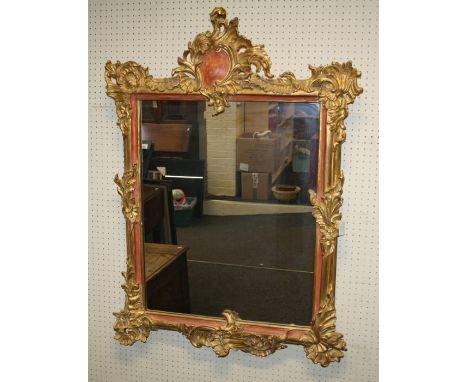 A 19th century carved giltwood wall mirror, the Rococo form frame enclosing a later plain rectangular plate. 112 x 80 cms.
