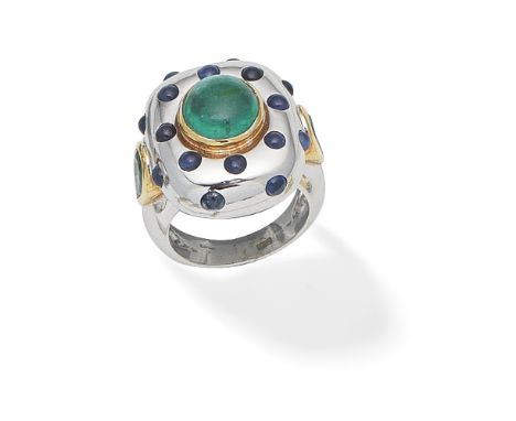 EMERALD AND SAPPHIRE DRESS RINGThe central circular emerald cabochon within a mount inlaid with sapphire cabochons, the shoul