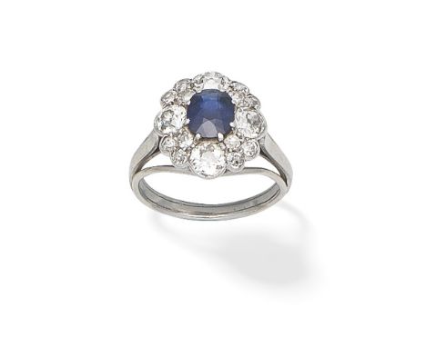 SAPPHIRE AND DIAMOND CLUSTER RINGThe oval-cut sapphire within a surround of old brilliant-cut diamonds, between trifurcated s