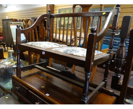 A small dark wood spindle back two-seater bench together with an occasional table