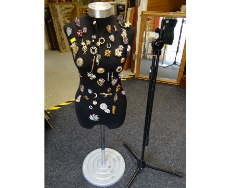 Mannequin with a parcel of costume jewellery brooches attached together with a microphone stand