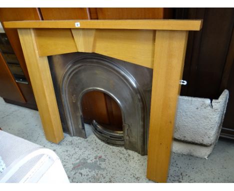 A modern light oak fire surround with metal insert