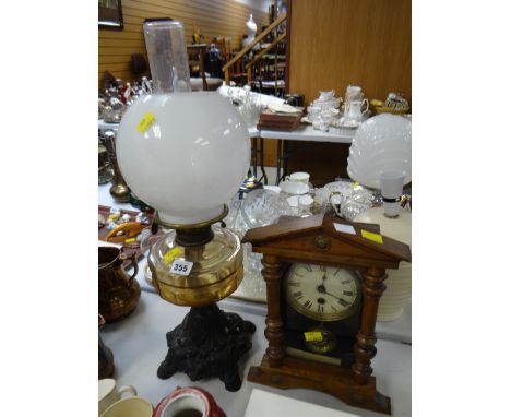 A vintage oil lamp with amber glass reservoir & metal base together with a wooden mantel clock