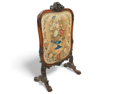 Victorian mahogany fire screen, ornately carved top, above an embroidered panel depicting a floral design and vase behind gla